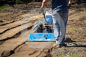 Rototiller tractor unit preparing soil dirt on outdoor garden