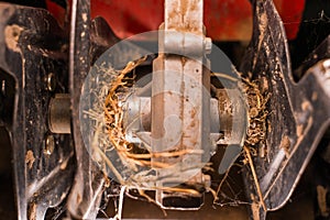 Rototiller of a walk-behind tractor with tangled dry grass close-up