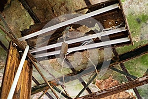 Rotted ceiling and damaged fluorescent light fixture in abandoned building