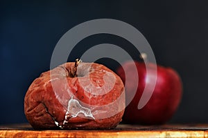 A Rotten Apple in the Foreground, A Fresh Apple Out of Focus In The Background. Good vs Bad. Antithesis Concept. Dark Background