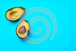 A rotten avocado cut in half on blue background. Copyspace on blue.