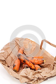 Rotten carrots on supermarket bag. Mouldy vegetables as wasted f