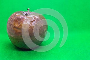 Rotten granny smith apple on green background