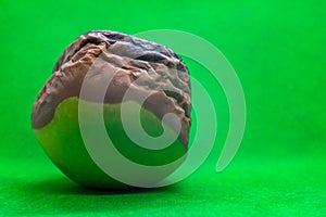 Rotten granny smith apple on green background