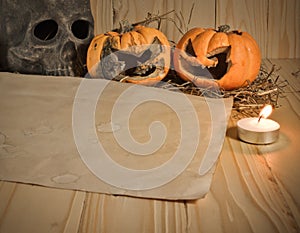 rotten Halloween pumpkin and old paper with candlelight and dry