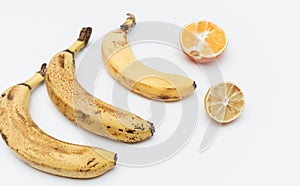 Rotten ripe bananas, half bad orange and lemon. Excessive consumption, wasting money concept