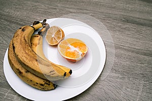 Rotten ripe bananas, half bad orange and lemon. Excessive consumption, wasting money concept