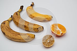 Rotten ripe bananas, half bad orange and lemon. Excessive consumption, wasting money concept