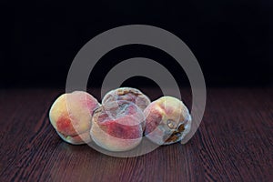 Rotten spoiled peaches on a black background