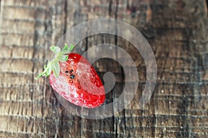 Rotten strawberries on a wooden background