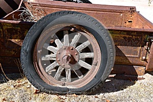 Rotten tire with wooden spokes on the wheel on a rusty box of a truck