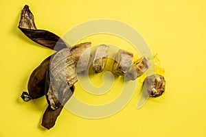 Rotten unhealthy banana on a yellow background