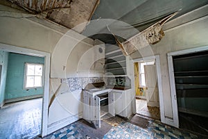 The rotting and decaying interior of an old kitchen in an abandoned home in Bannack Ghost Town. Ceiling is collapsing photo