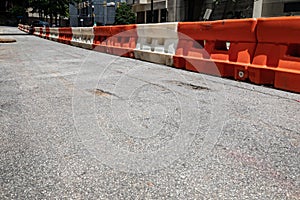 Rough asphalt street with orange and white traffic barricade divider, urban city street scene, creative copy space