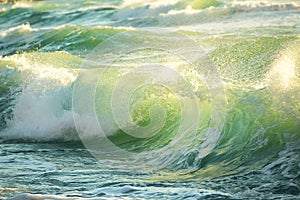 Rough colored ocean wave breaking down, sunrise shot