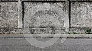 A rough concrete wall with a gray sidewalk and an asphalt road. Urban background for copy space photo