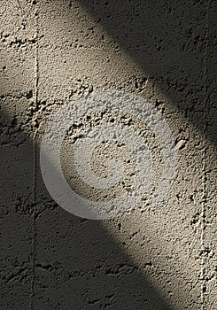 Rough concrete wall surface with an angled light beam creating a dramatic shadow.