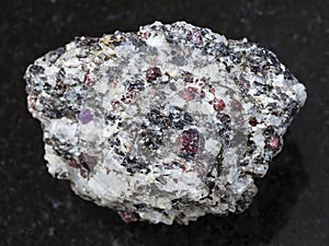Rough corundum crystals in gneiss stone on dark