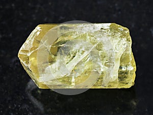 rough crystal of yellow apatite gemstone on dark photo