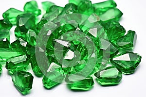 rough emeralds scattered on a white table