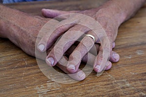 The rough hands of a manual labourer on a wooden table.