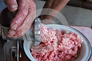 Rough hands of old man make mincemeat of vintage meat grinder. Close up