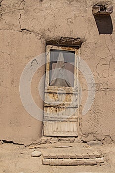 Rough hewn wood door with damaged screen and wooden porch in adobe mud pueblo dwelling in Taos New Mexico