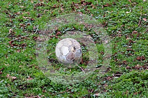 Rough looking football left out in all weathers on untidy grass