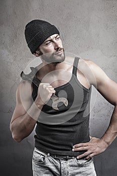 Rough man holding a wrench on his shoulder