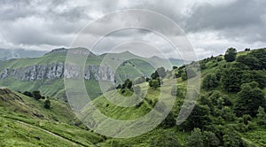 Rough mountain landscape with steep limestone slopes and green meadows photo