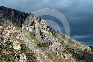Rough mountain peak with dar rainy clouds in the background around Contrada Rebuttone, Italy