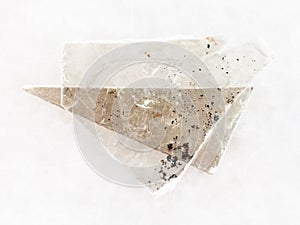 rough muscovite mica lamina on white marble