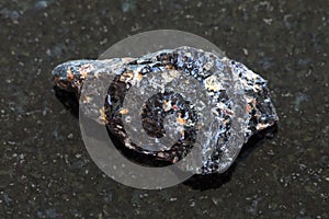 rough obsidian (volcanic glass) stone on dark