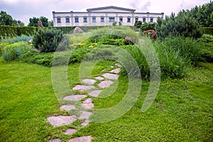 Rough ornamental stone path paved in green lawn on park walkway.