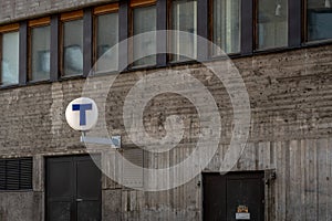 Rough outdoor concrete subway station building with T sign in Stockholm.