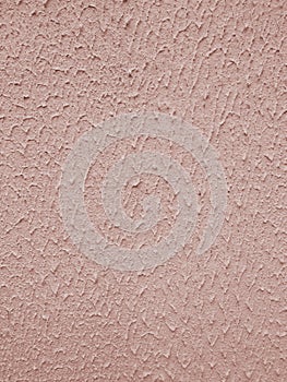 Rough pink plaster surface on the wall of the building