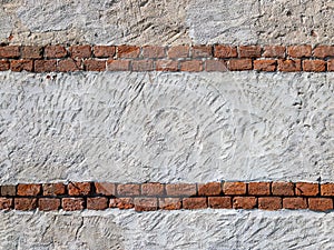 Rough plaster wall texture with rows of exposed antique red bricks,