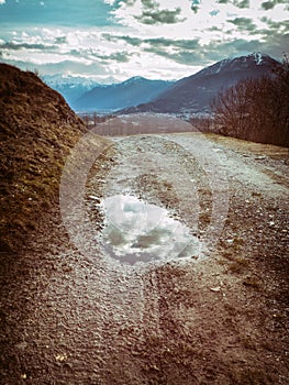 Rough road with pool and reflecting clouds