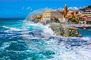 rough sea big waves crash on small port of Nervi in Genoa in Italian Riviera of liguria in beautiful sunny day