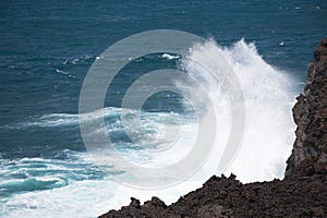 Rough sea shore with waves chrashing against the black lava rocks