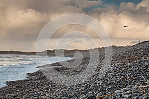 Rough stone beach at dusk, dark dramatic sky with sun light beams, Strandhill town, county Sligo, Ireland, Atlantic ocean. Rescue