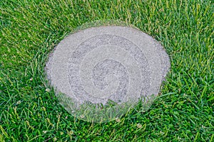 Rough surfaced, flat, round, concrete tile in the green grass photo