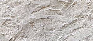 The rough texture of a poorly plastered light-colored wall. An uneven surface with bumps and depressions. Background