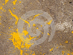 Rough textured concrete surface with patched of yellow flaking paint