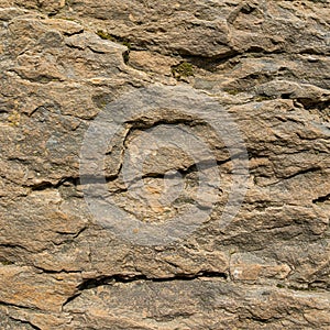 Rough textured rock surface with layered, uneven formations. The color varies photo