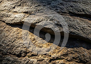 Rough-textured rock surface with visible stratification. The rocks