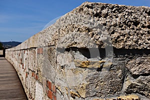 Rough textured stone and brick low parapet wall. blue sky