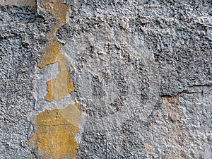 Rough wall texture of an old building with signs of decay and damage, pieces of the facade left with old cement showing as cool