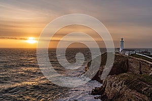 Rough weather off the lighthouse at sunset Isle of Anglesey North Wales