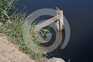 Rough wooden stairs with handrails made of boards on the shore of a pond